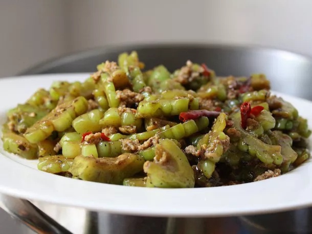 A white plate containing stir fried bitter melon