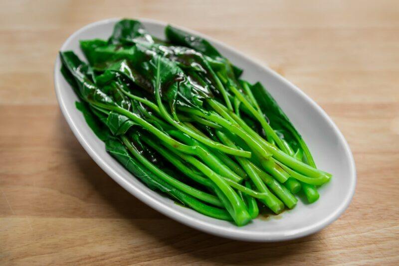 A white plate with half a dozen or more pieces of Chinese broccoli or Chinese kale