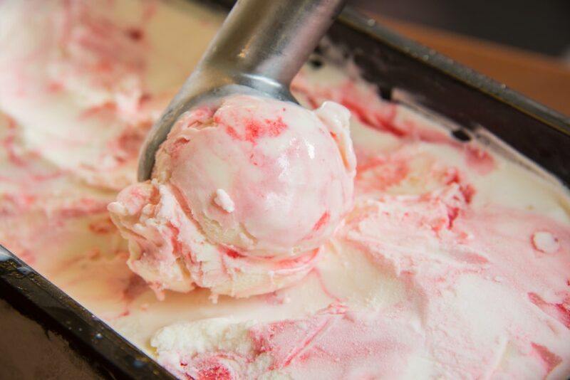 Strawberry cheesecake ice cream being scooped out for dessert