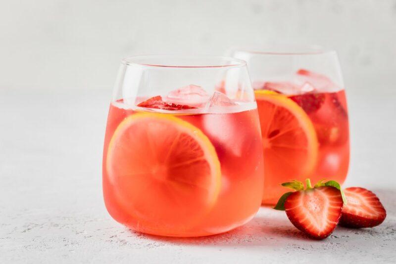 Two glasses containing a strawberry lemonade punch on a light table