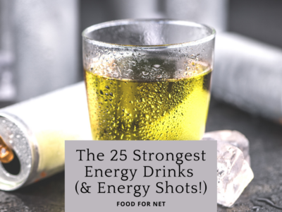 A glass of energy drink and empty energy drink cans on a table