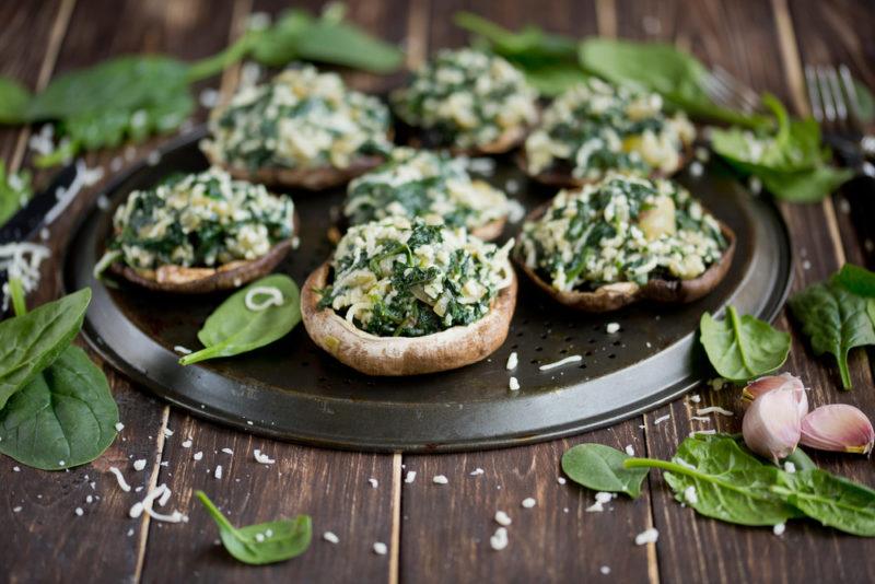 A selection of vegan stuffed mushrooms on a plate that's on a wooden table