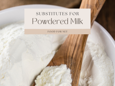 A white bowl filled with powdered milk and a wooden spoon of more powdered milk, looking at substitutes for powdered milk.