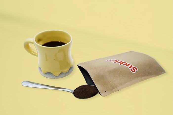 A sachet of coffee with a cup