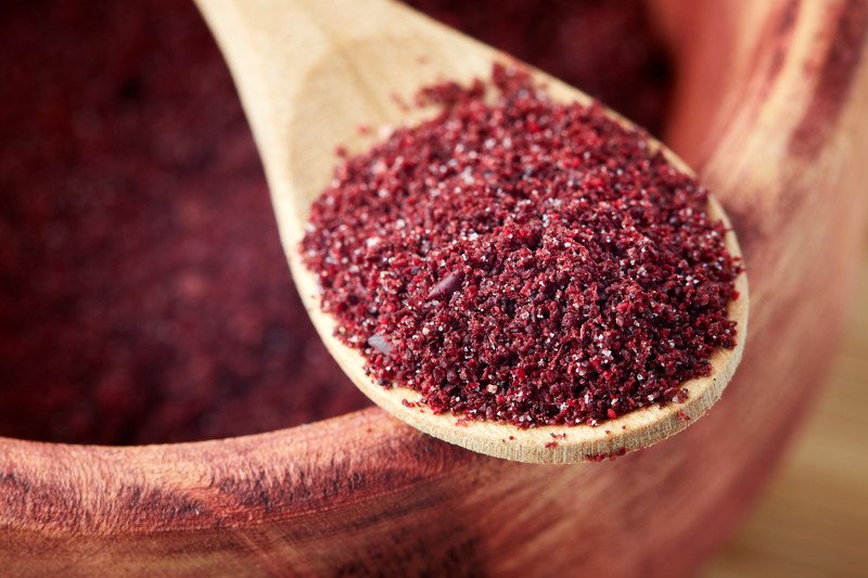 closeup image of wooden spoon full of sumac