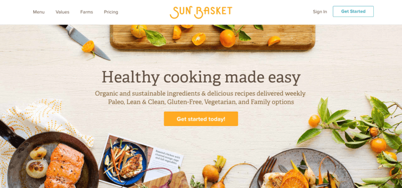 sun basket website screenshot showing a chopping board, a pan that includes salmon and various other healthy ingredients. 