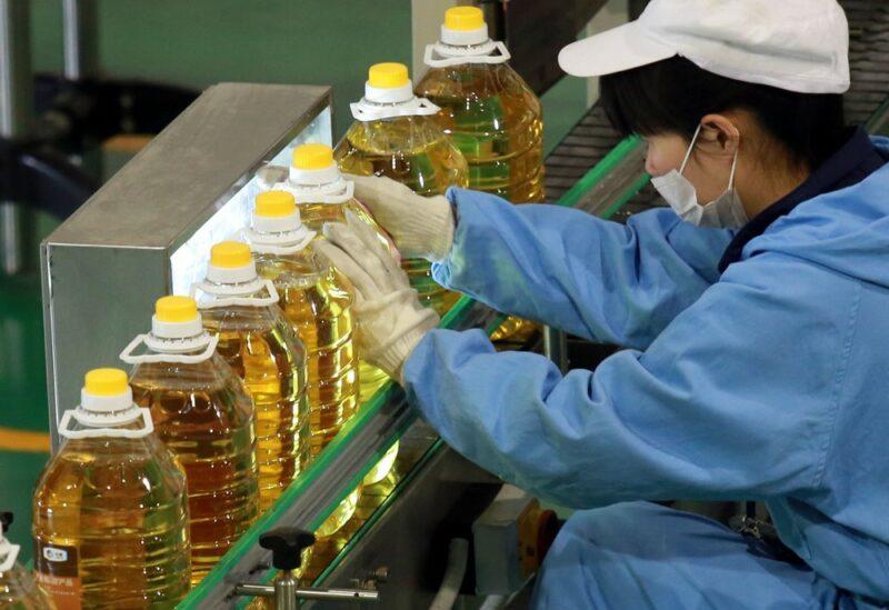 A factory worker wearing a mask packaging plastic bottles of sunflower oil