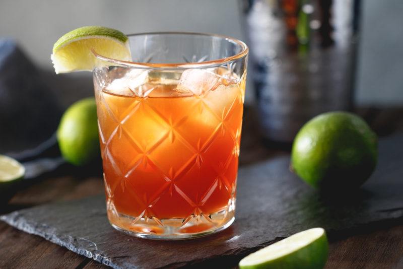 A Surfer on Acid cocktail in a glass with limes and a cocktail shaker on the table