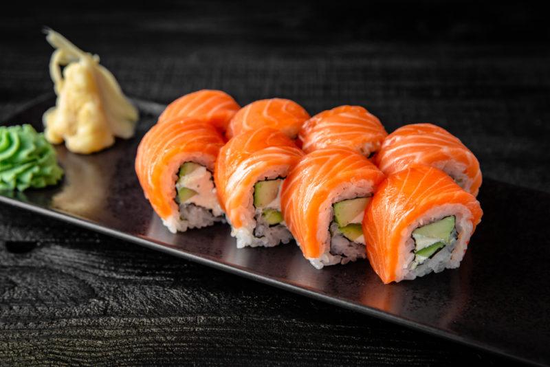 A black dish of sushi next to seasonings at the end