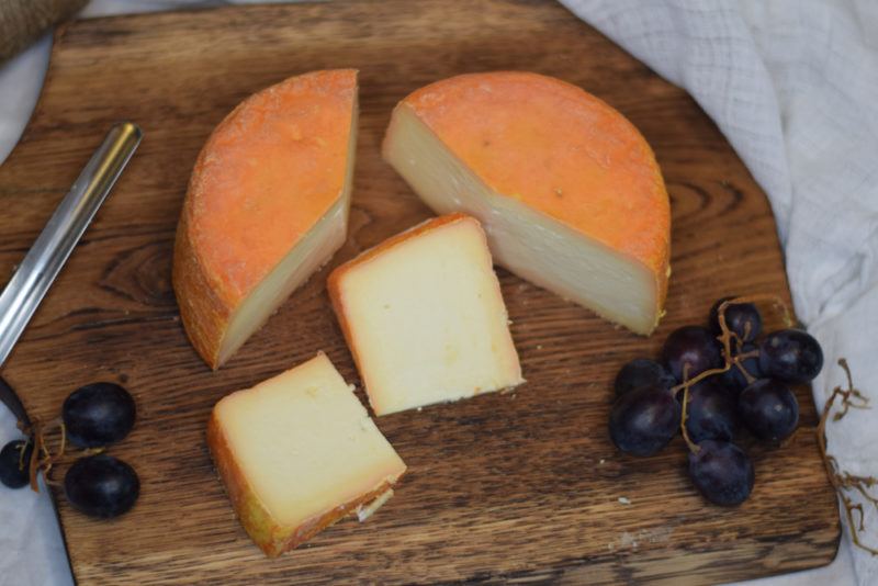 Top down image of Taleggio with grapes on a wooden board