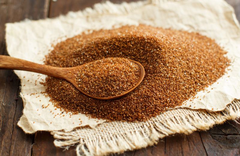 A pile of teff and a spoon on wooden paper