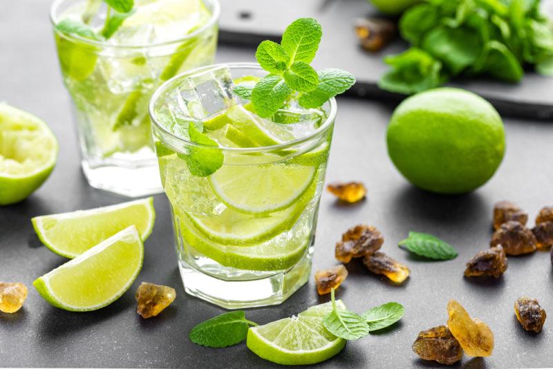 Two tequila moijito cocktails on a table with various garnishes on a table