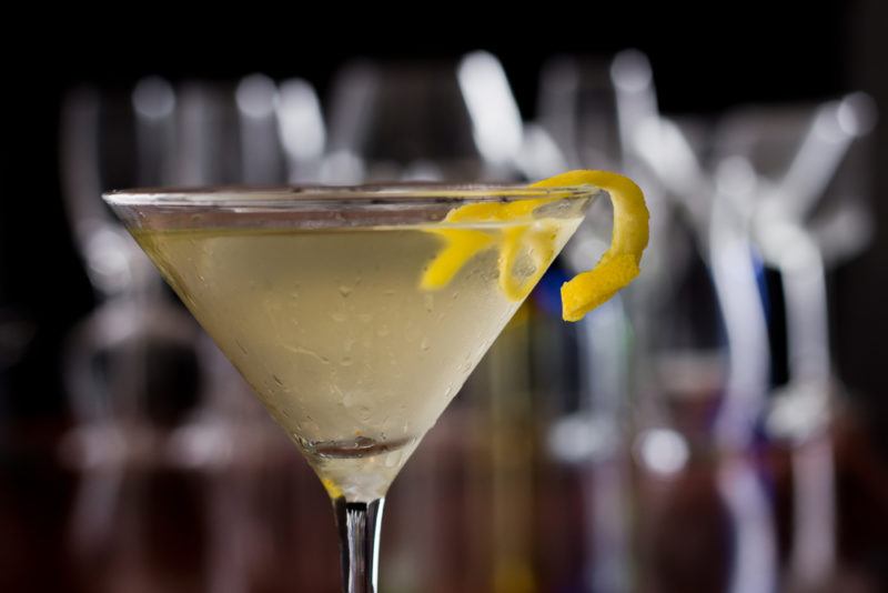 A yellow tequini cocktail with empty glasses in the background