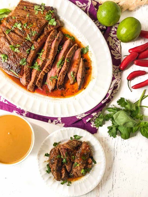 A white table with sliced pieces of Thai marinated flank steak