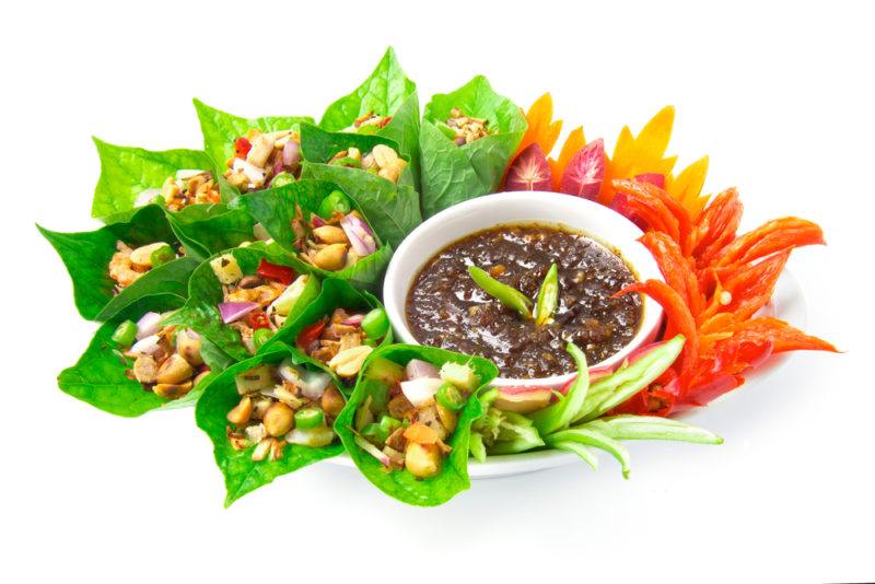 A collection of appetizers served in spinach leaves with dip