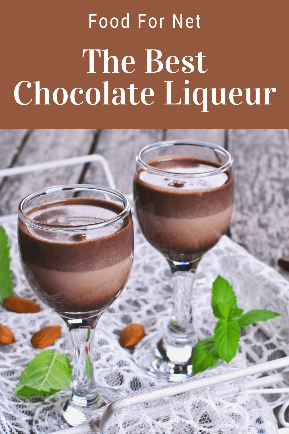 Two glasses of chocolate liqueur cocktails on a white tray with green leaves and red berries