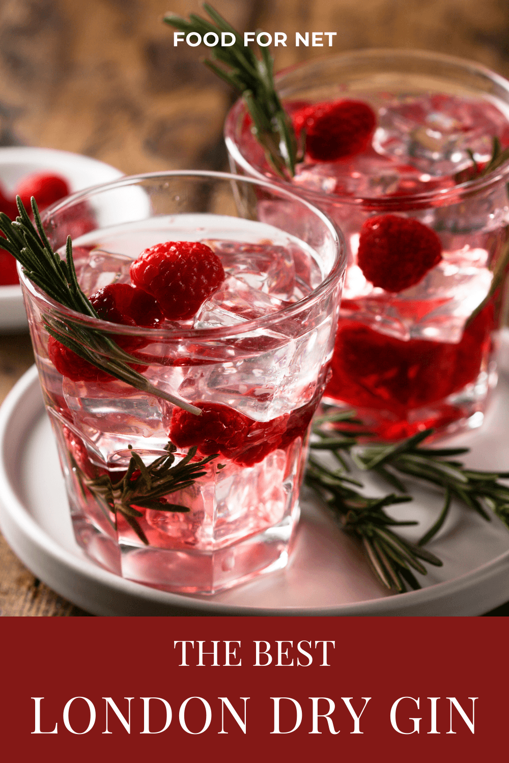 Two glasses of a gin cocktail with fresh raspberries, next to a small bowl of the berries