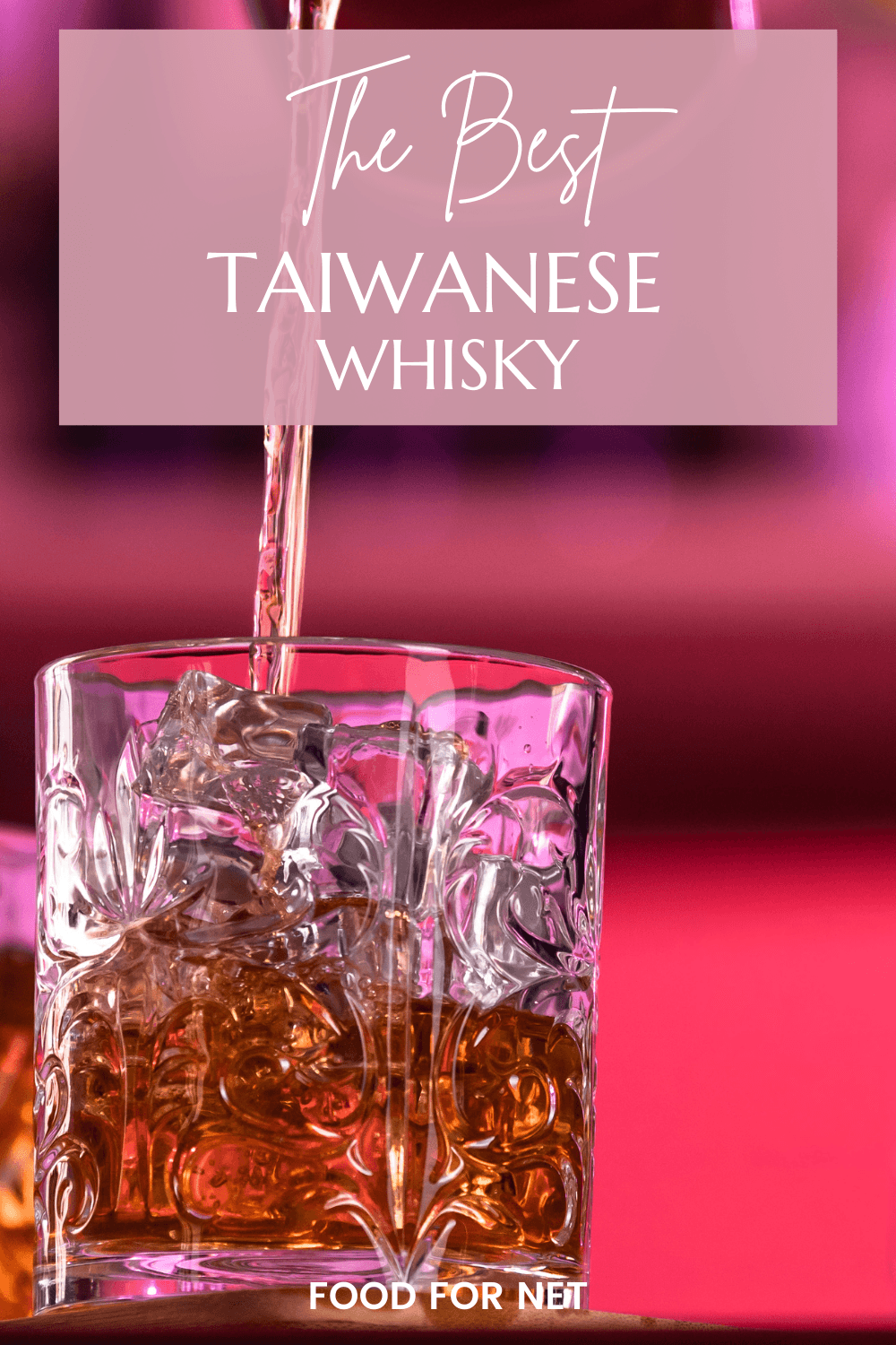 Best Taiwanese Whisky. A glass of whiskey and ice against a pink background, where the whiskey is being poured into it