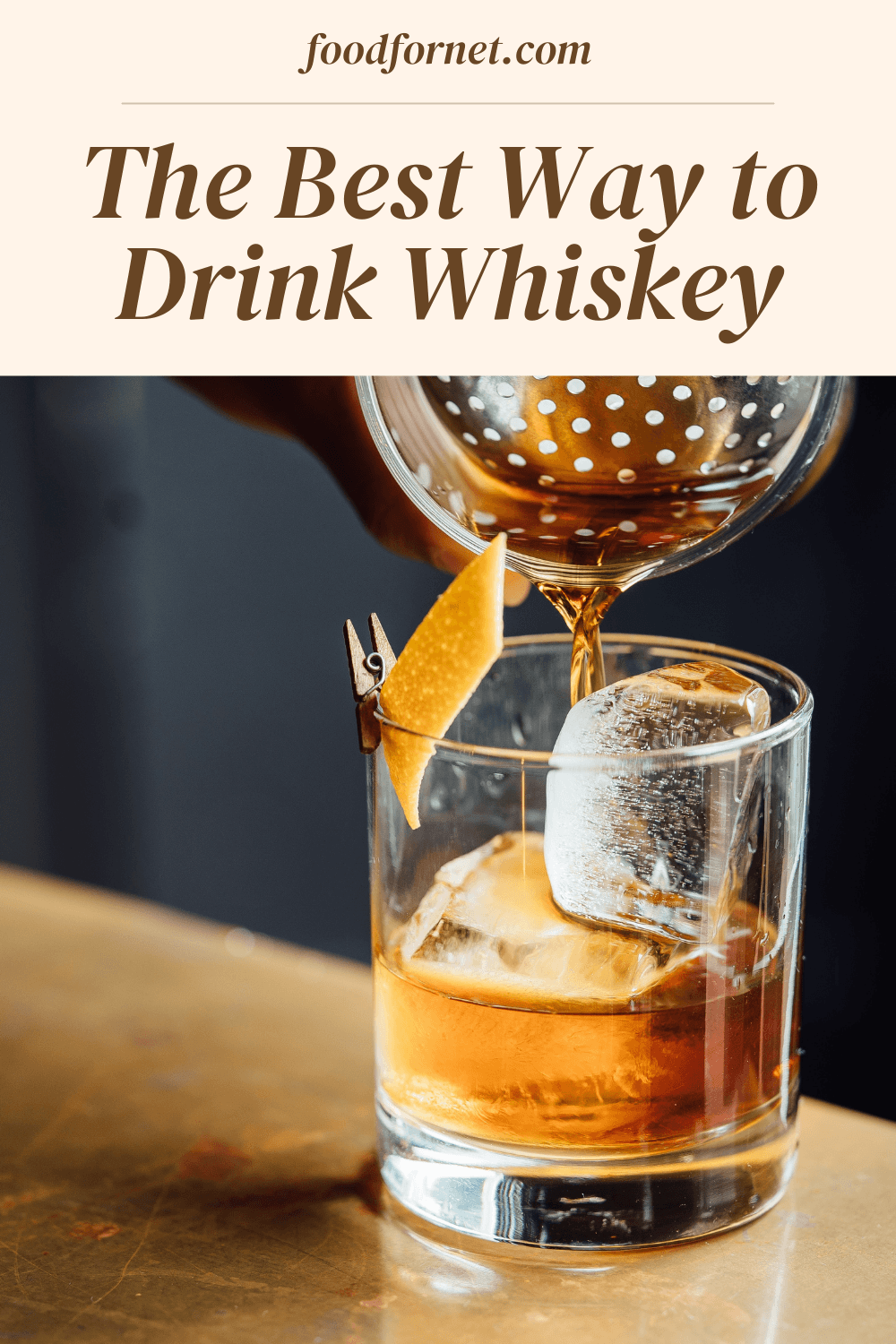 Whiskey being poured into a glass with balls of ice and a citrus twist, highlighting the best way to drink whiskey