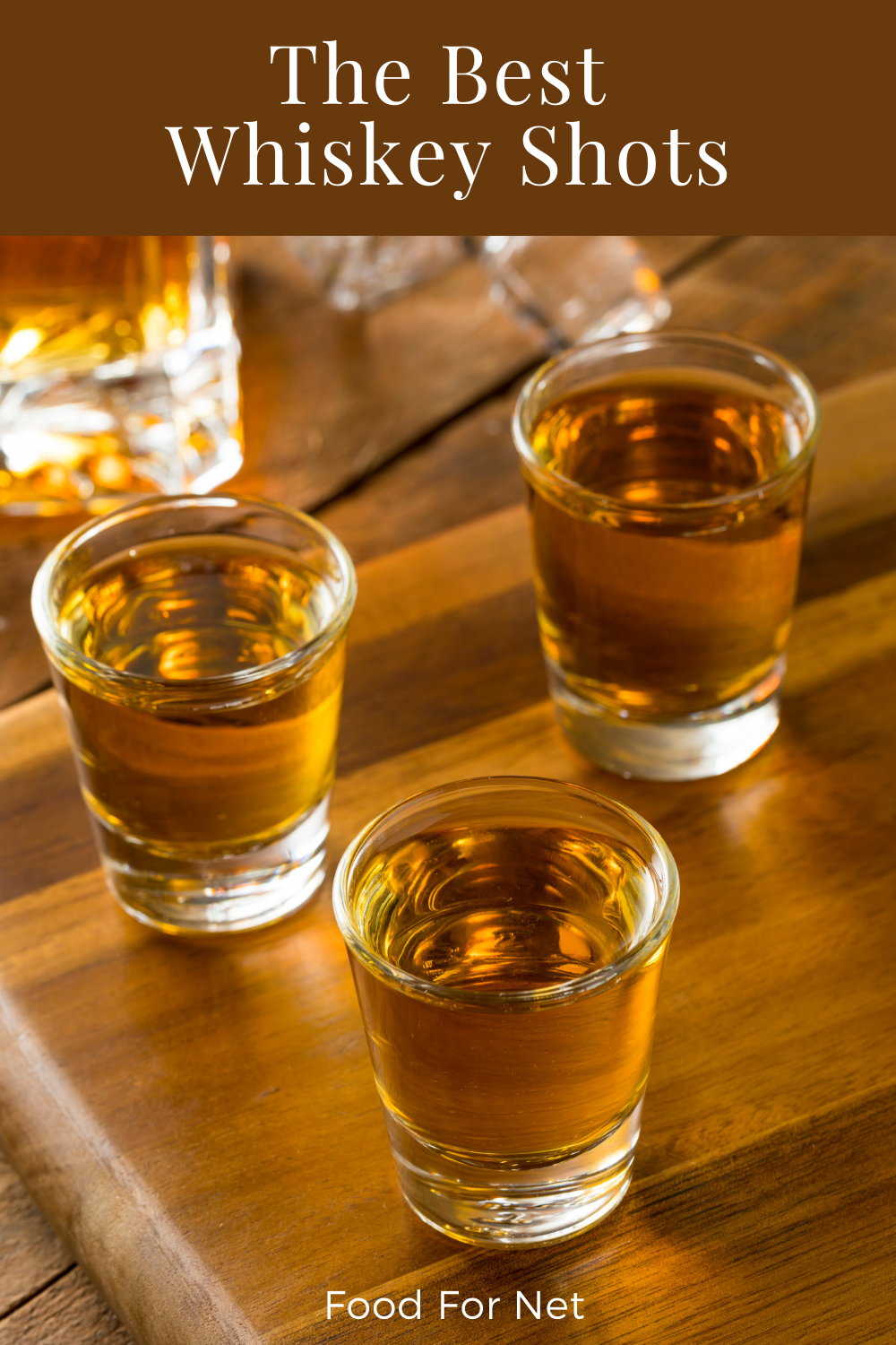 Three glasses of whiskey shots on a wooden board