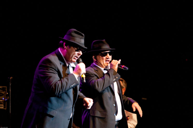 The Blues Brothers preforming live against a black background