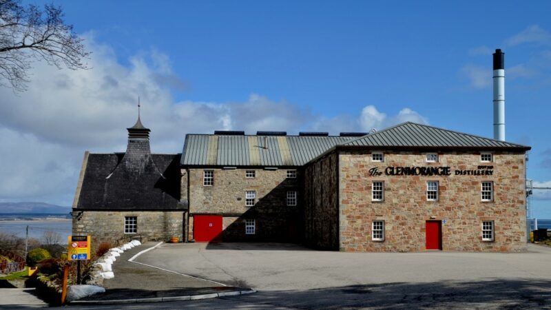 The large Glenmorangie distillery contrasted against a light blue sky with clouds