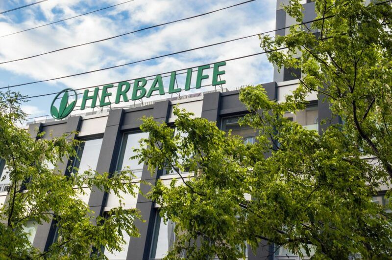 Looking up at a building with the Herbalife logo, with trees in front