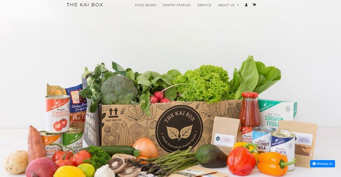 A box filled with various fresh fruit, veggies and tins of produce. 