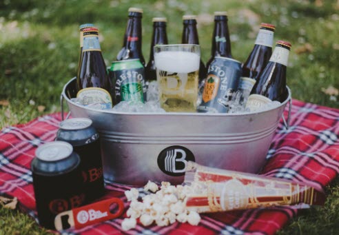 Metallic tub filled with ice and various bottles & cans of beer.