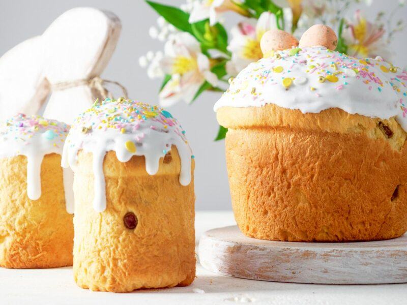 Three tall Russian Easter kulich cakes, each decorated with white frosting