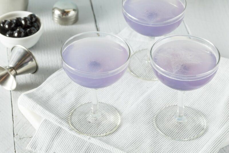 Three light purple aviation cocktails on a white cloth