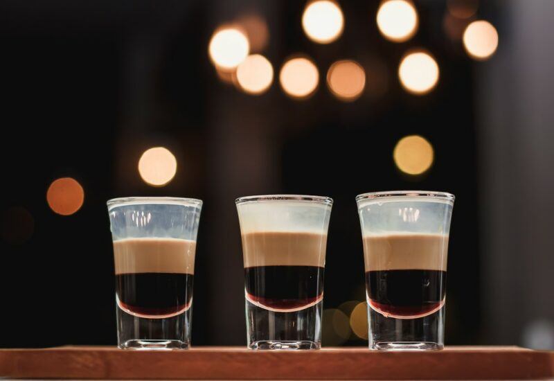 Three baby Guinness shots on a table with out of focus lights in the background