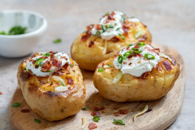 Three baked potatoes with cheese, bacon, and sour cream