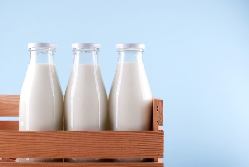 A brown crate with three bottles of milk