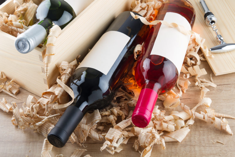 Three bottles of wine lying on their side in a box with packing material