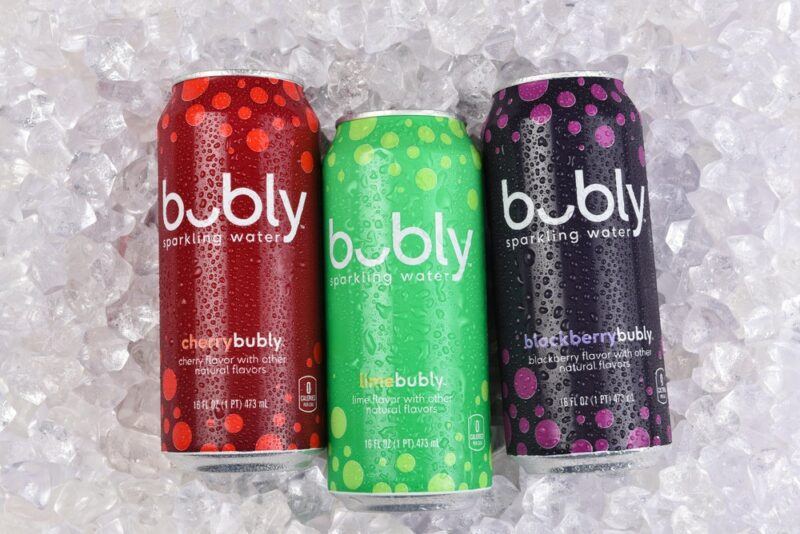 A bed of ice with three tall cans of Bubly sparkling water, one red, one green, one purple