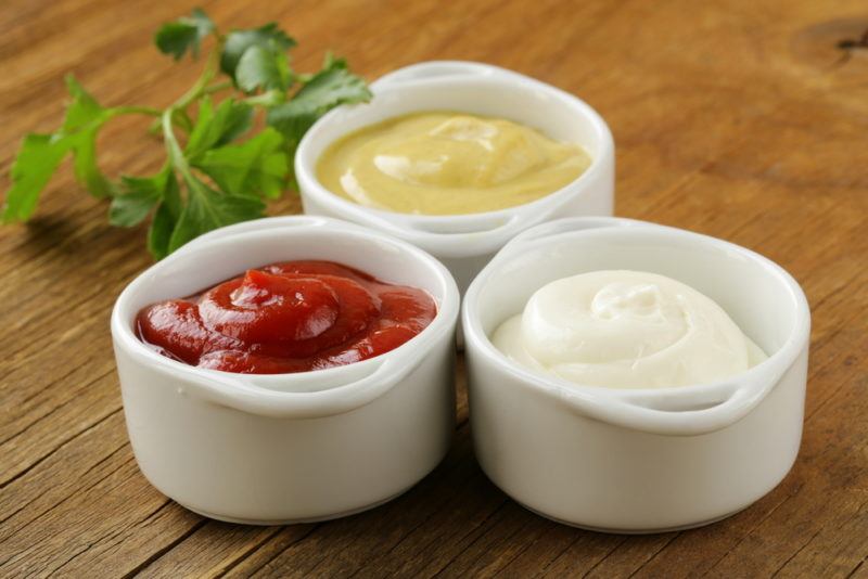 Three containers of condiments | Food For Net Three white dishes with condiments, including mustard, ketchup, and mayonnaise