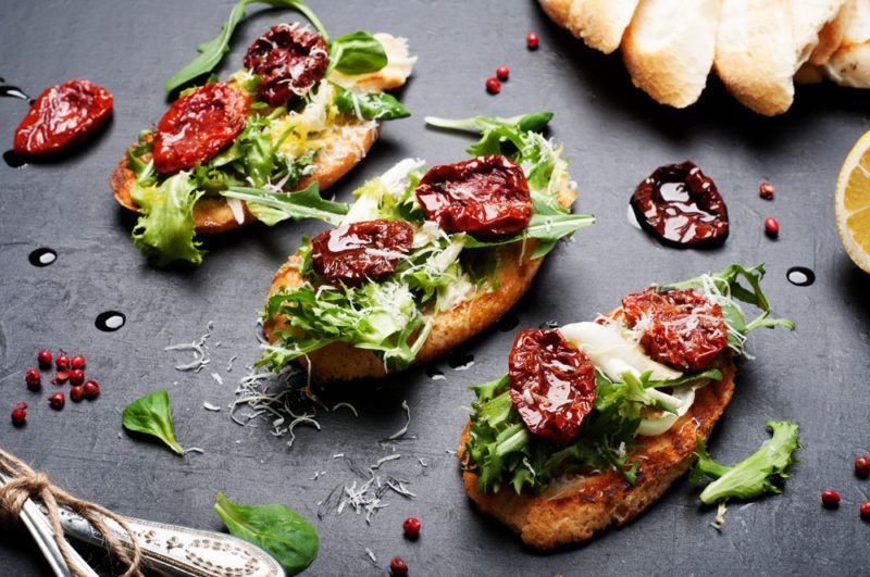 Three pieces of bruschetta on a table with different toppings