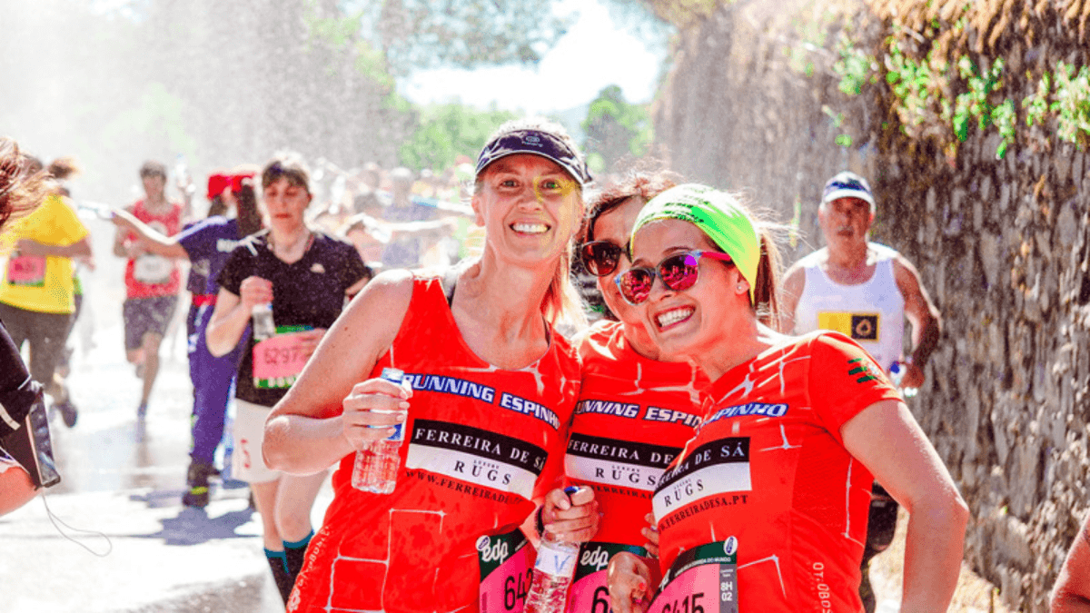 Three female runners in red shirts at a race on a sunny day 