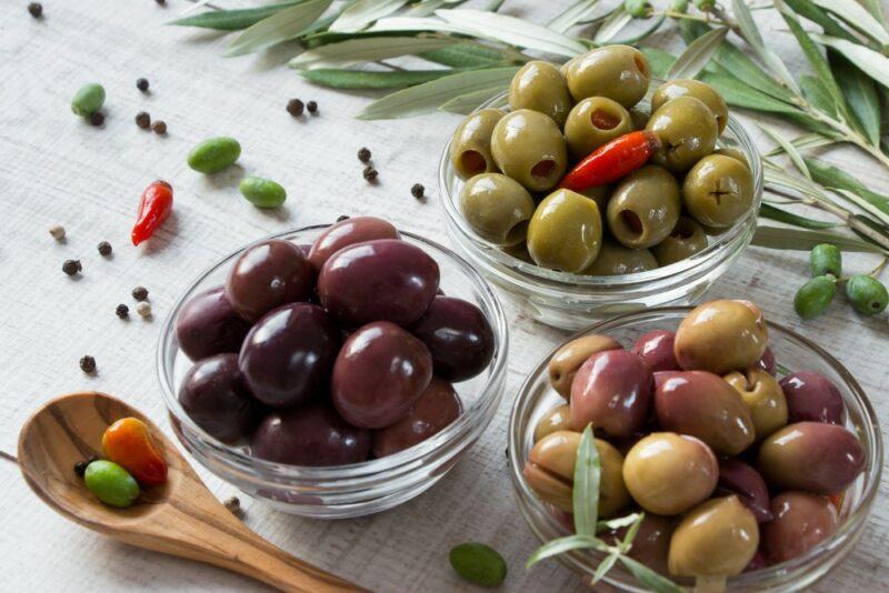 Small glass bowls with different types of olives, one with green olives, one with kalamata olives, and one with mixed olives