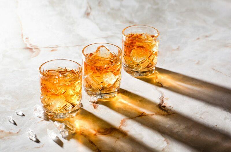 Three glasses containing an affinity cocktail that are casting shadows