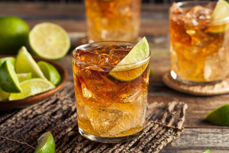 Three glasses of a Bundaberg libra cocktail on a wooden table with limes scattered around