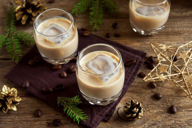 Three glasses of a creamy cocktail called Fireball French toast on a wooden table surrounded by seasonal decorations