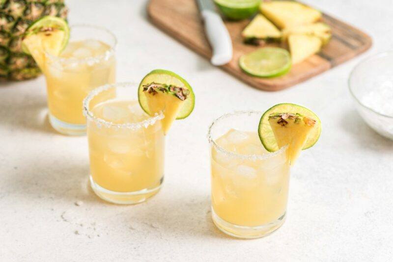 Three glasses of a pineapple matador cocktail with small pieces of fruit as a garnish