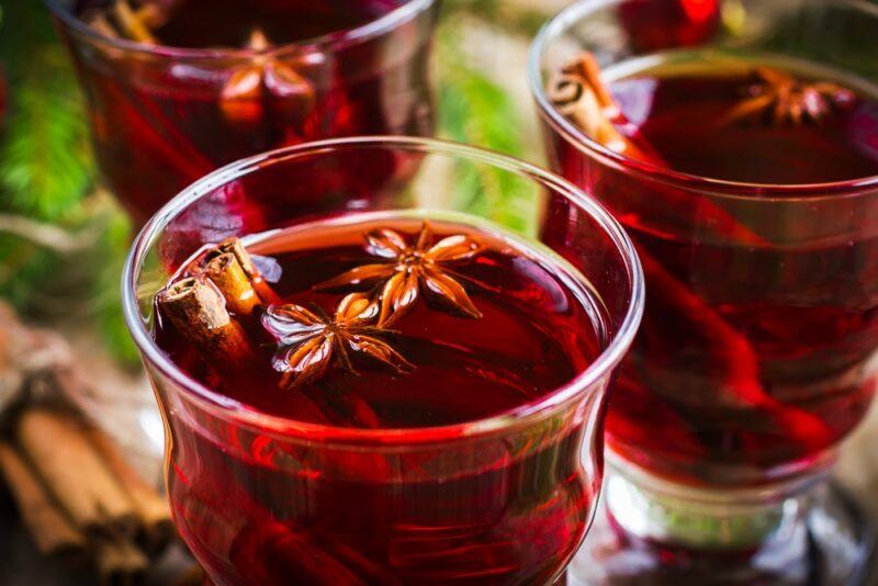 Three glasses containing a hot pomegranate and vermouth mulled wine cocktail