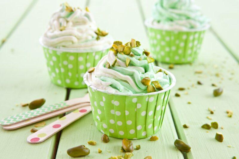 Three lime green spotted paper cups filled with green and white frozen yogurt