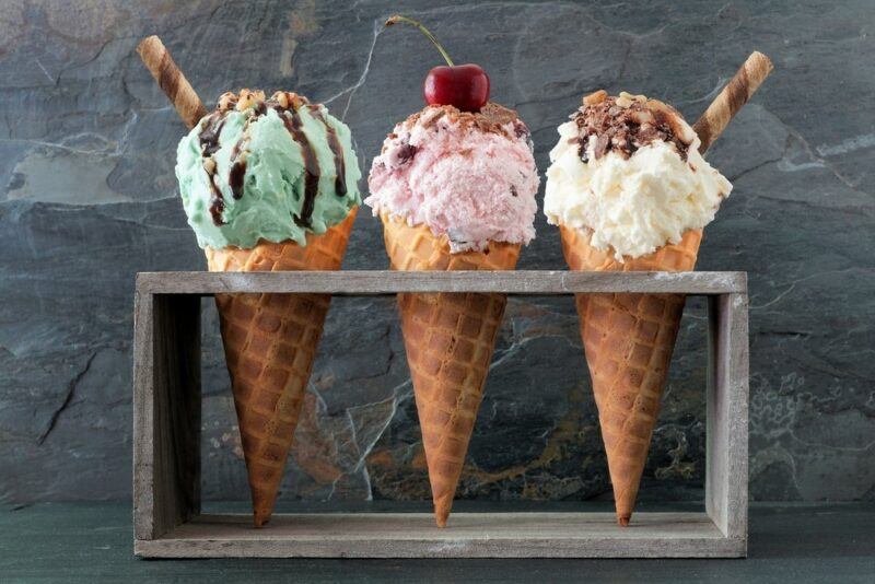 Three ice cream cones in a stand, each with a different type of topping