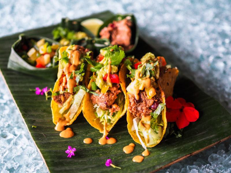 A wooden board with three types of jackfruit tacos