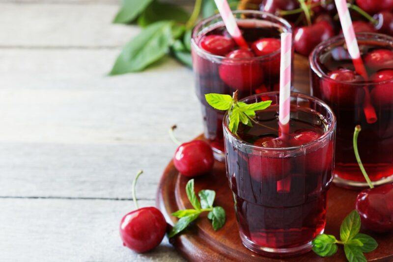 Three or four glasses of cherry juice with cherries and straws