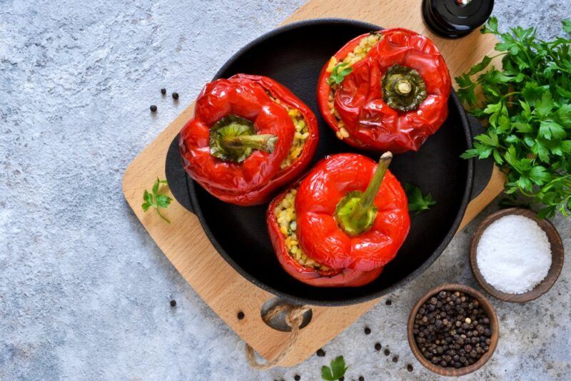 A black dish containing three red bell peppers that have been stuffed